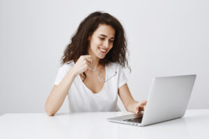 Frau sitzt am Laptop und bearbeitet Formulare mit Canva.