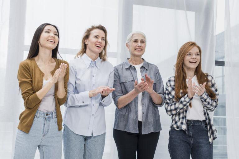 Vier Frauen klatschen Beifall bei einem Seminar.