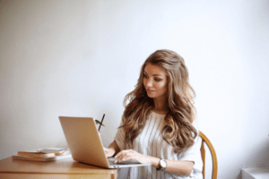 Frau sitzt am Laptop und bearbeitet Elemente in Canva für Ihre Schulungsunterlagen im Kosmetikstudio.